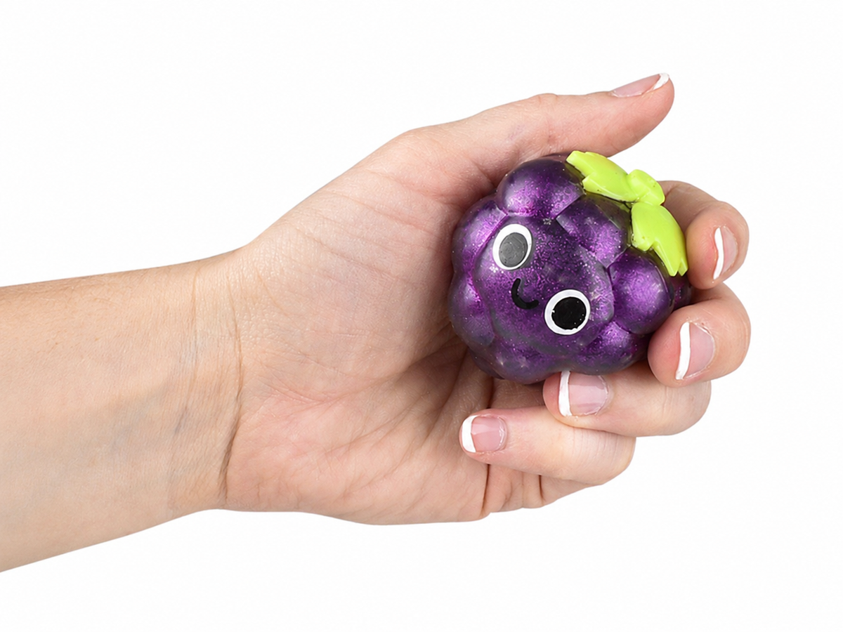 Hand holding a purple glitter grape squishy toy with green leaves and cartoon face